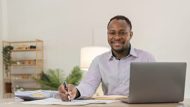 Portrait of handsome African black young business man working on laptop at office desk...