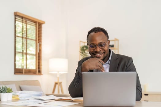 Portrait of handsome African black young business man working on laptop at office desk...