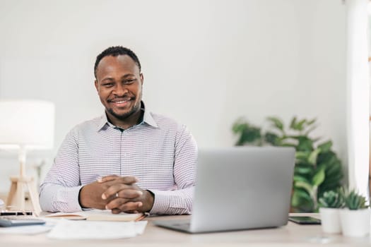 Portrait of handsome African black young business man working on laptop at office desk...