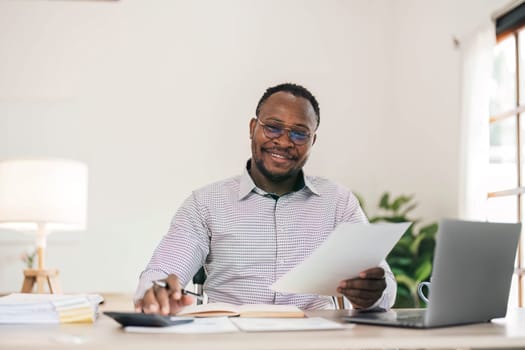 Portrait of handsome African black young business man working on laptop at office desk...