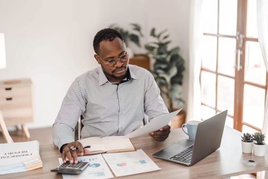 Portrait of handsome African black young business man working on laptop at office desk...