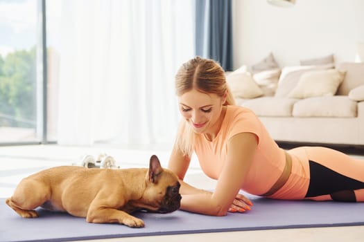 Laying down on the mat. Woman with pug dog is at home at daytime.