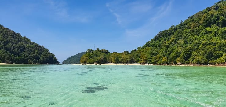 Scenic view of Koh Mak Island's peaceful white sand beach and crystal clear turquoise sea water bay with tropical tree