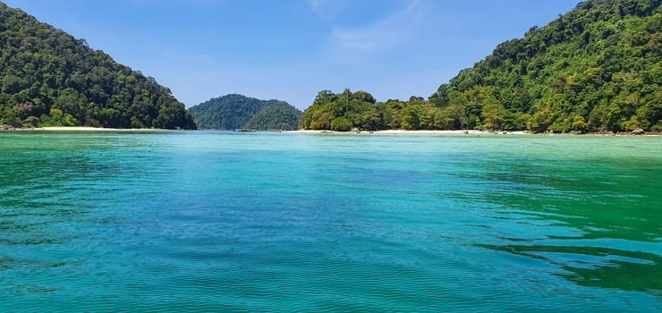 Scenic view of Koh Mak Island's peaceful white sand beach and crystal clear turquoise sea water bay with tropical tree