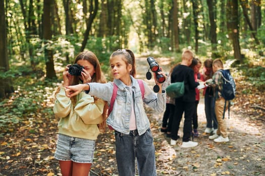 Looking for a path. Kids in green forest at summer daytime together.