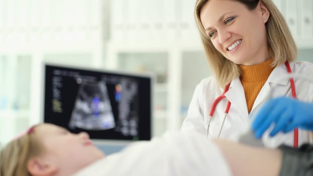 Doctor pediatrician conducting abdominal ultrasound examination of internal organs of child in clinic. Diagnosis of treatment of diseases of gastrointestinal tract in children concept