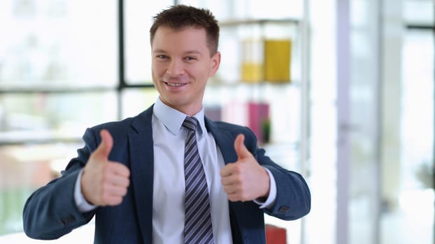 Successful businessman in suit showing thumbs up in office. Success and career growth in business concept