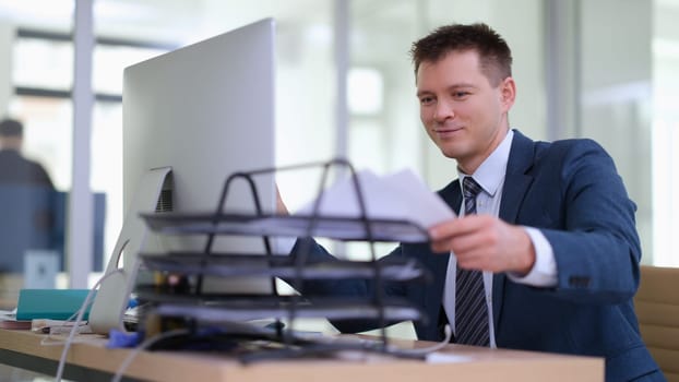 Smiling businessman taking documents to work in office. Paperwork concept