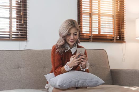 woman beautiful happy young woman resting on comfortable sofa, using cellphone application, web surfing useful information, playing games, shopping online.