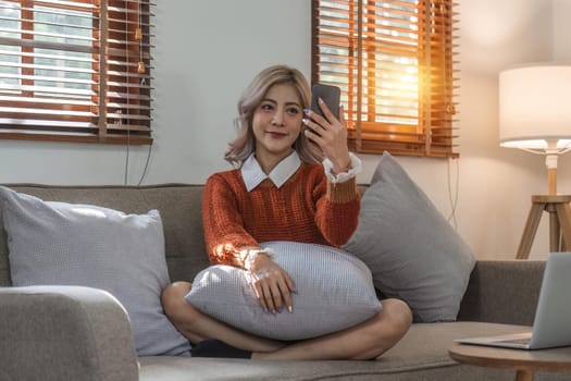 Young woman on video call, relaxing and surfing through internet with cellphone.