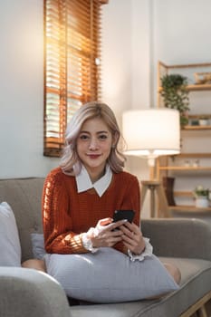 woman beautiful happy young woman resting on comfortable sofa, using cellphone application, web surfing useful information, playing games, shopping online.