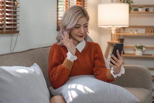 Young woman on video call, relaxing and surfing through internet with cellphone.