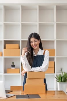 Young pretty asian start up business woman in apron working with online parcel box warehouse selling online product.