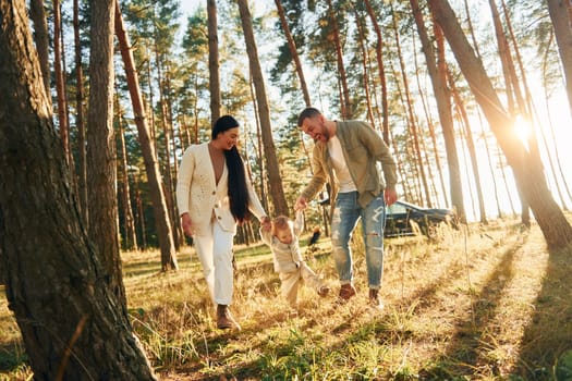 Weekend rest. Happy family of father, mother and little daughter is in the forest.