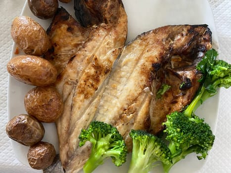 top view of dorada fish grilled with baked potato broccoli. Healthy food.