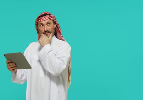 Online shopping in Middle East. Arab man holds tablet and selects goods and services. High quality photo