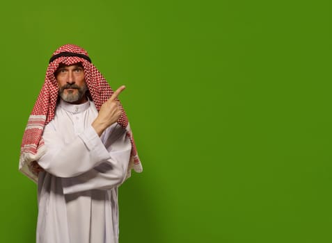 mature Muslim man in traditional dishdasha points his finger towards copy space symbolizing concept of Sharia law, Islamic legal system based on teachings of Quran and Hadith. authority, leadership, and principles of justice and ethics within the legal framework of Sharia law, with copy space for additional text or design elements. High quality photo