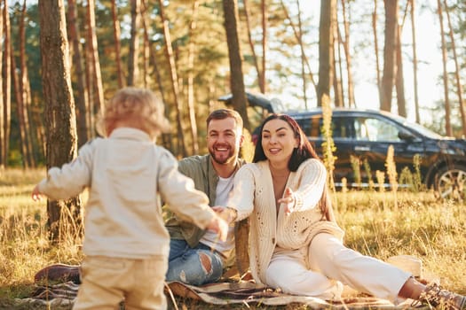 Positive emotions. Happy family of father, mother and little daughter is in the forest.