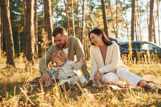 Positive emotions. Happy family of father, mother and little daughter is in the forest.