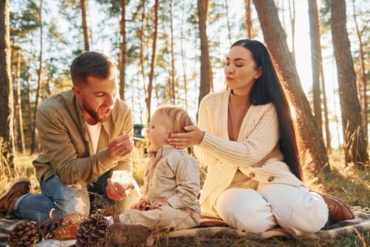 In the forest. Happy family of father, mother and little daughter.