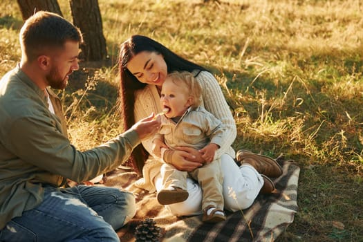 In the forest. Happy family of father, mother and little daughter.