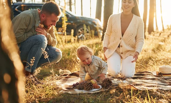 Playful mood. Happy family of father, mother and little daughter is in the forest.