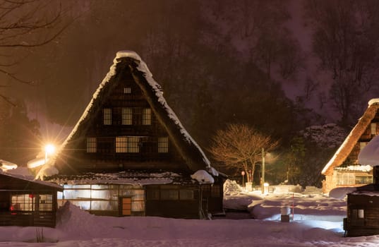 Traditional A-frame house in Gokayama amid snow and mist at night. High quality photo