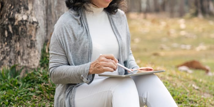 Asia grandmother 60s using tablet vacation watching Social news holiday in park.