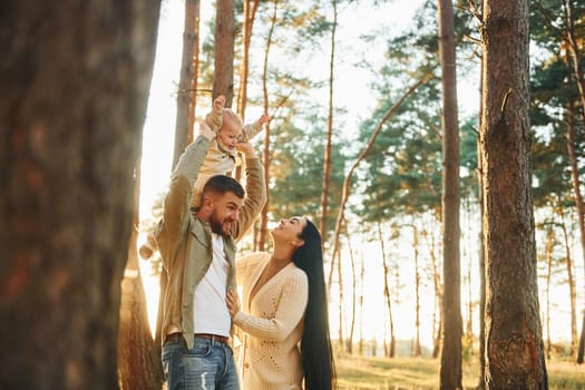 Joy and happiness. Family of father, mother and little daughter is in the forest.
