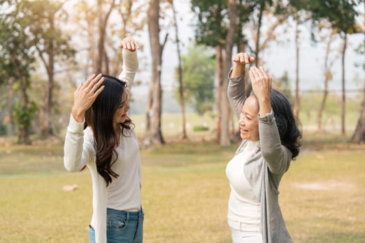 Asia grandmother 60s and Lovely granddaughter gently stretch body in the park.