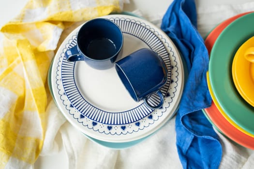 A pyramid of brightly colored bowls, plates and cups of different sizes and colors on the kitchen table. Scandinavian style, minimalism. View from above