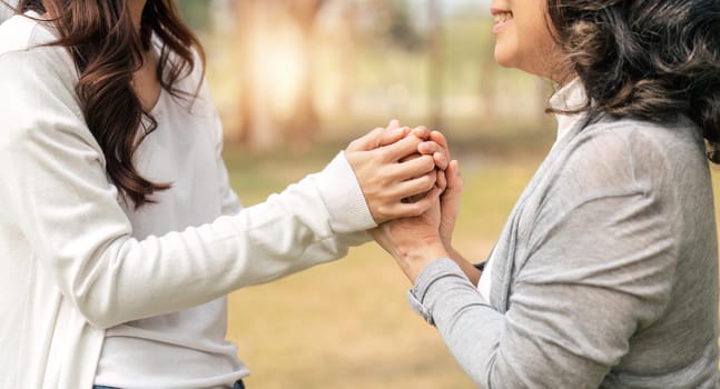 granddaughter consoling her senior grandmother and touching hand when in park.