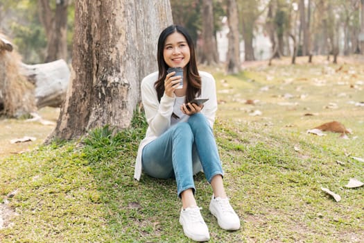 young smiling woman in on in park outdoors rest use mobile cell phone see news online and sip coffee.