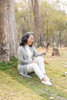 Asia grandmother 60s using mobile smartphone video call with her family or friends vacation holiday in park.