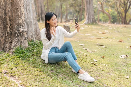 young woman in on in park rest use mobile cell phone video call to family or friends.