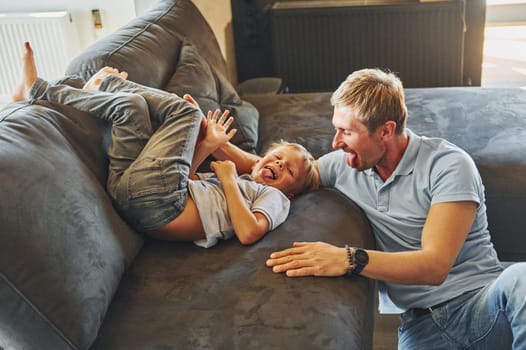 Playing and having fun. Father and son is indoors at home together.