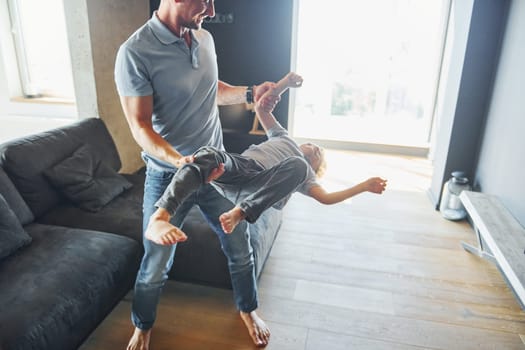 Man holding boy and having fun. Father and son is indoors at home together.