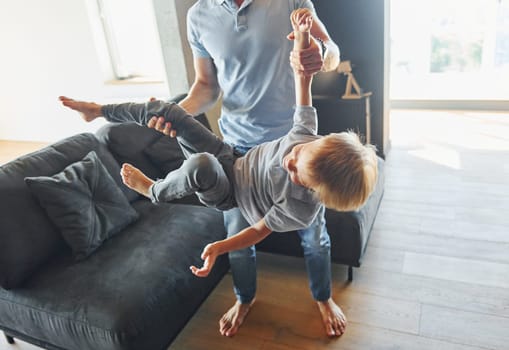 Man holding boy and having fun. Father and son is indoors at home together.