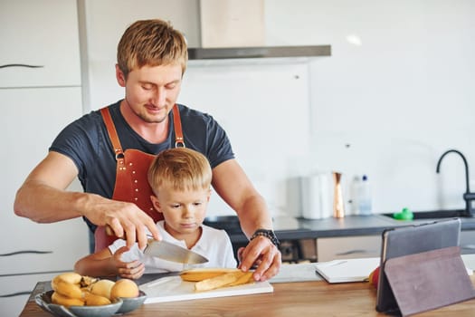 On the kitchen with food. Father and son is indoors at home together.