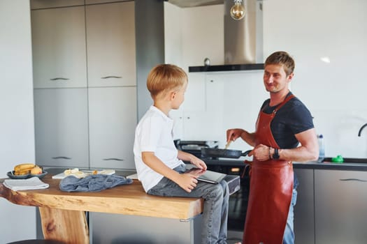 Preparing some food. Father and son is indoors at home together.