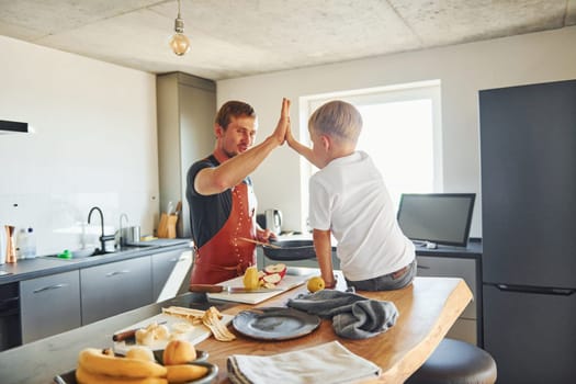 Preparing some food. Father and son is indoors at home together.