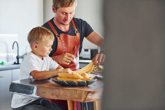 Preparing some food. Father and son is indoors at home together.