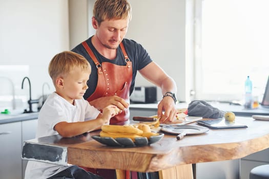 Conception of culinary. Father and son is indoors at home together.