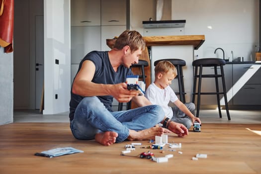 Weekend rest. Father and son is indoors at home together.