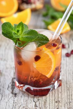 The cocktail is made from pomegranate and orange juice with tequila or gin, with the addition of tonic. Served in a glass with ice, orange slices with pomegranate and a sprig of mint. Cocktail recipe for any party.