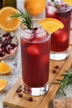 Pomegranate orange holiday punch with ice and rosemary. This is a sweet, tart and refreshing cocktail perfect for celebrating any party.