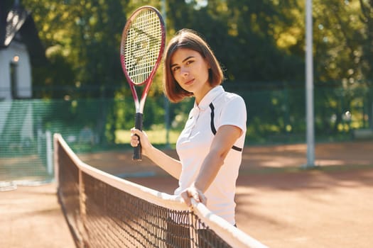 Near the net. Female tennis player is on the court at daytime.