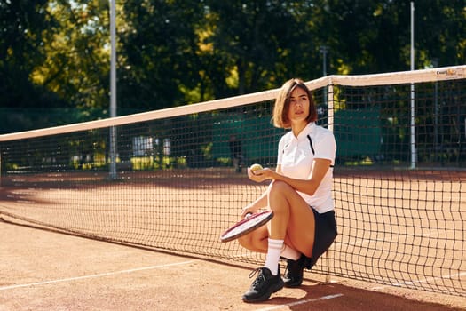 Near the net. Female tennis player is on the court at daytime.