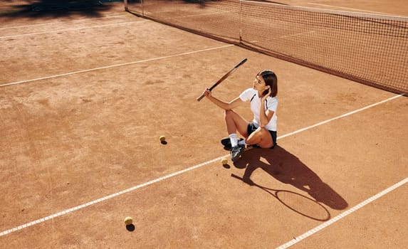 Near the net. Female tennis player is on the court at daytime.