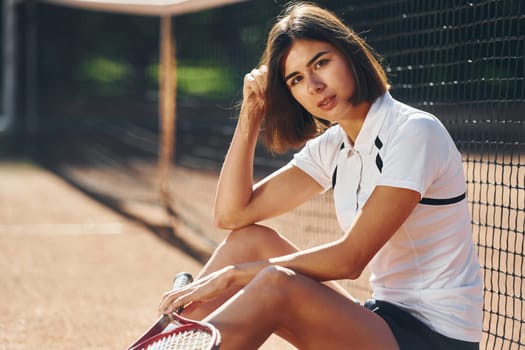 Looking at the camera. Female tennis player is on the court at daytime.
